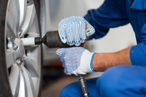 mechanic with screwdriver changing car tire P8D5VFA